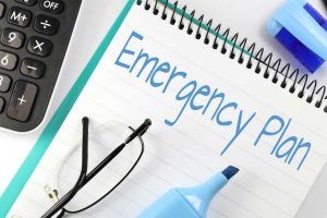 White note pad with the words Emergency Plan written on it with a blue marker.